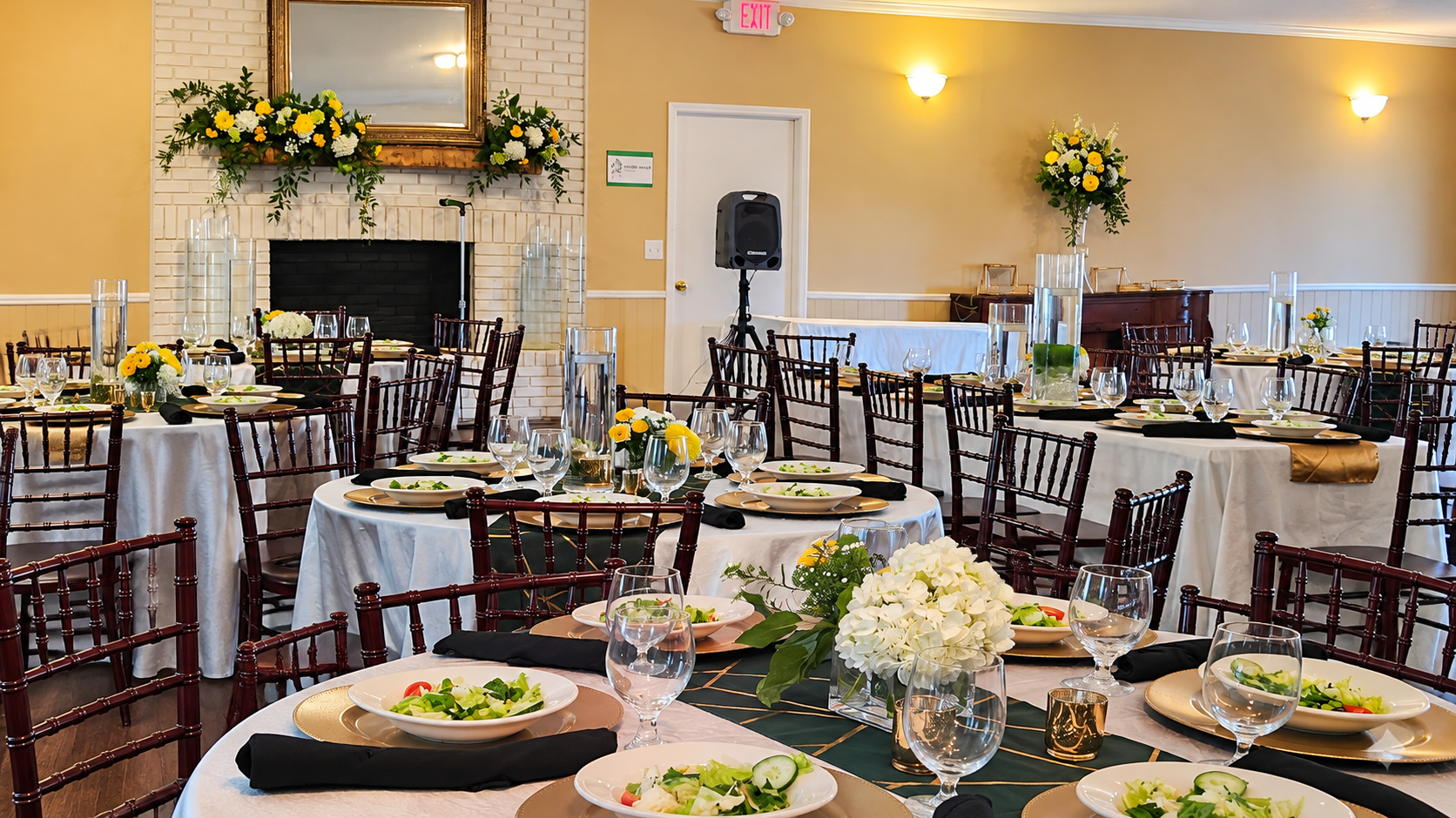 Edgar’s Steakhouse dining room with set tables, yellow and white floral arrangements, and a brick fireplace